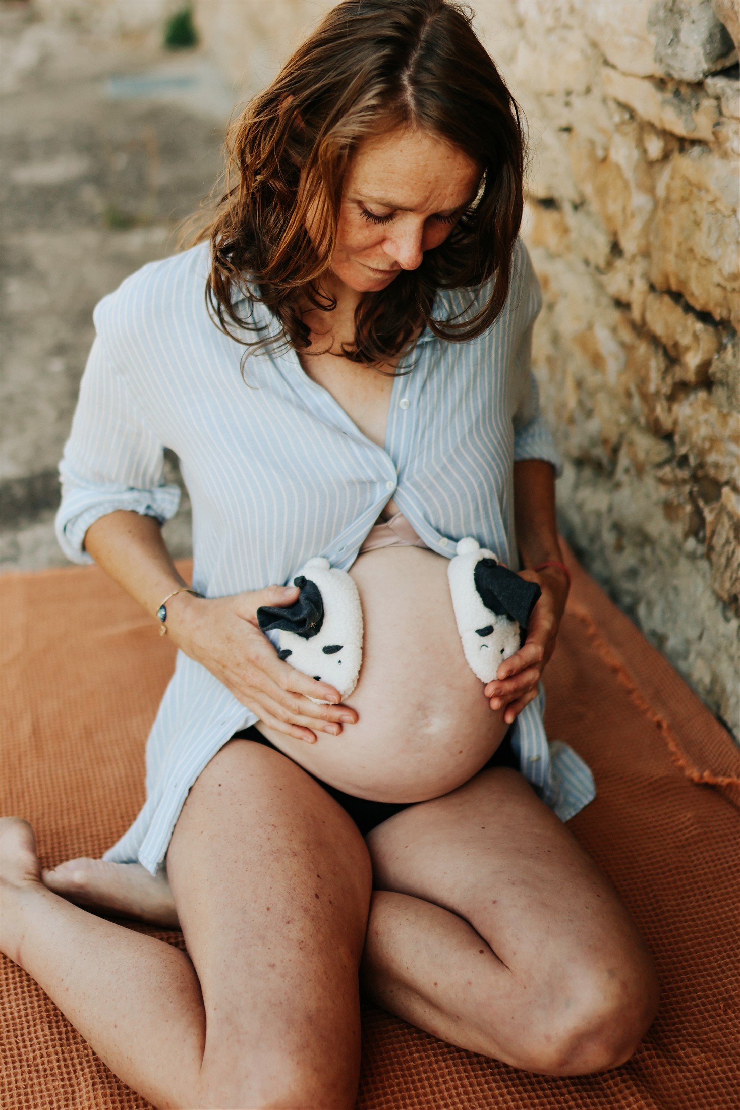 Future maman avec des chaussons en forme de chien sur son ventre